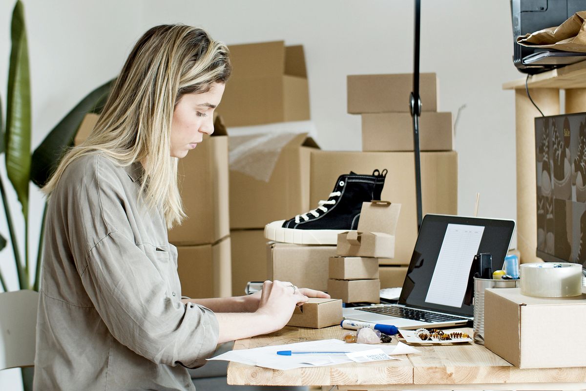Vendedora empacando pedidos de su tienda online en cajas de cartón